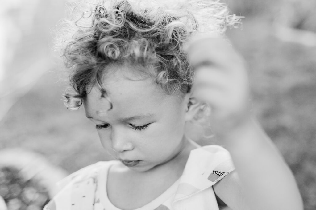 A close up black and white image of a little curly haired girl. 