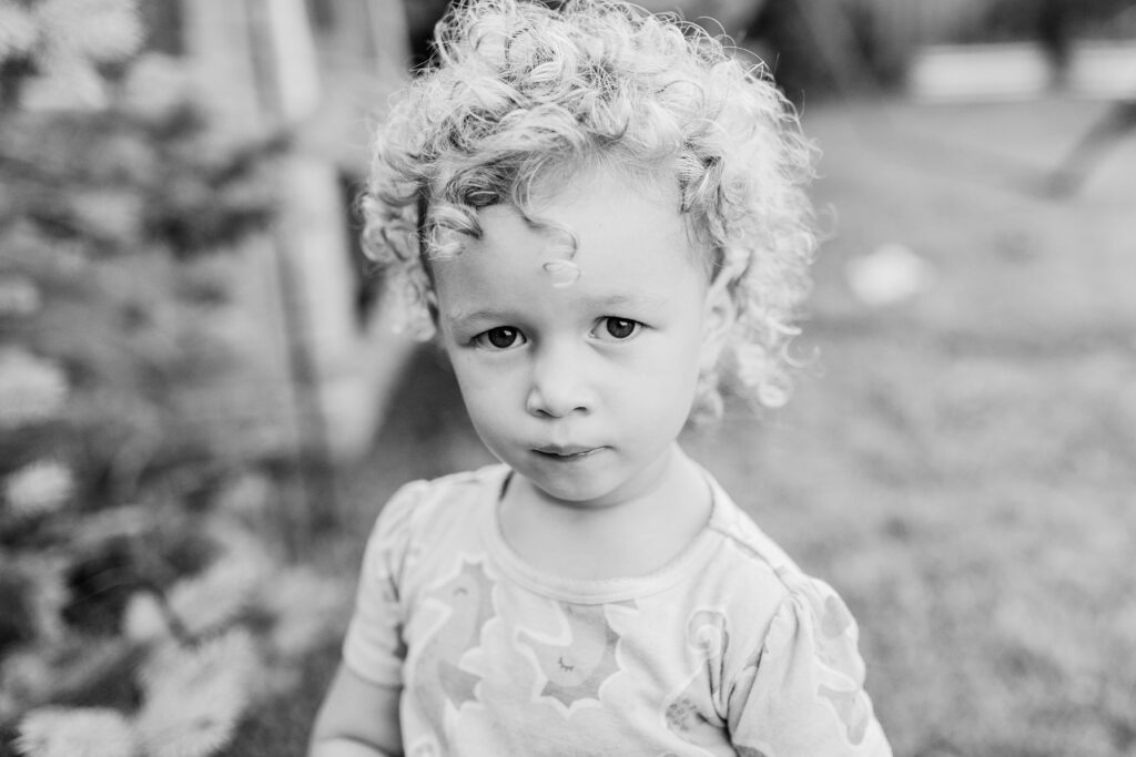 A black and white image of a curly-haired little girl. 