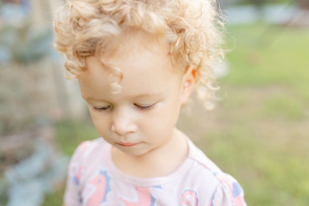 A close-up image of a curly-haired little girl during her family photo session.

