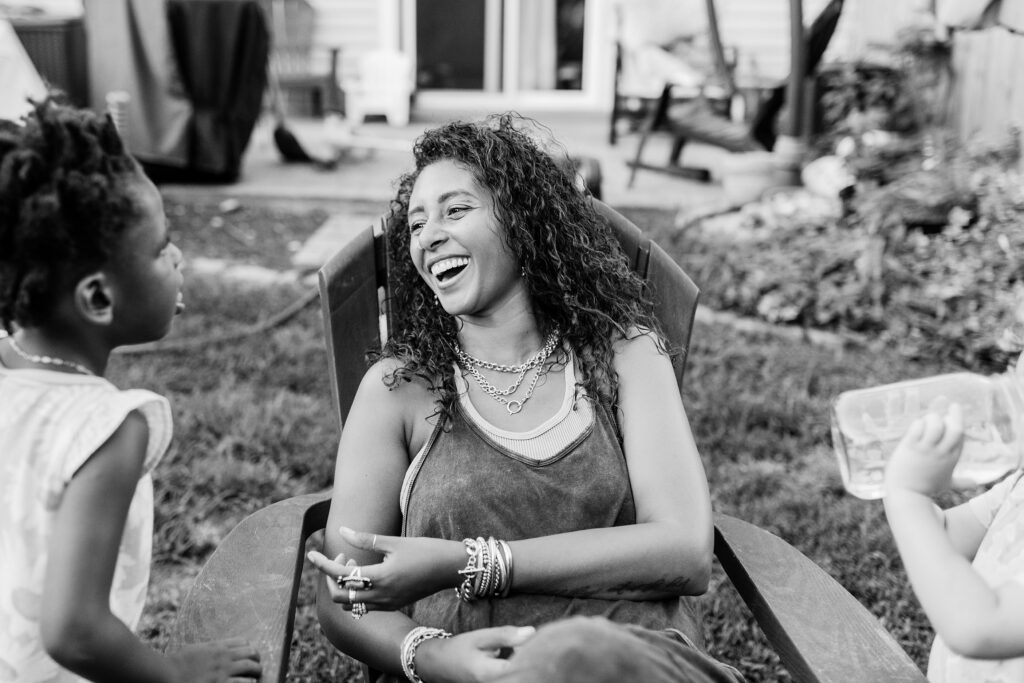 A mom laughing while enjoying her daughters during their backyard family session in Lexington KY.