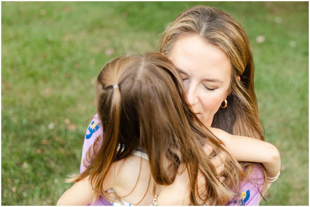 A mom holds her daughter and whispers in her ear during a family photography session in Lexington KY.