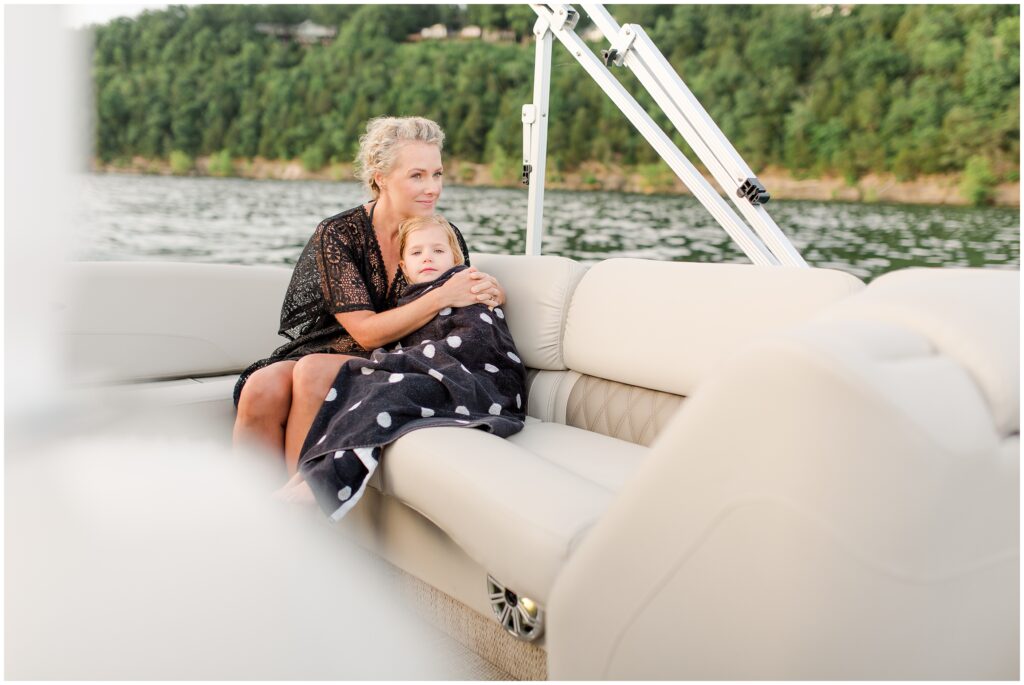 A mother keeping her daughter warm on a boat ride.